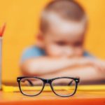 boy_sitting_ubfocused_glasses_in_focus._Concept_problem_of_ophthalmology_correction_of_myopia._back_to_school._Selective_focus._upset_child.
